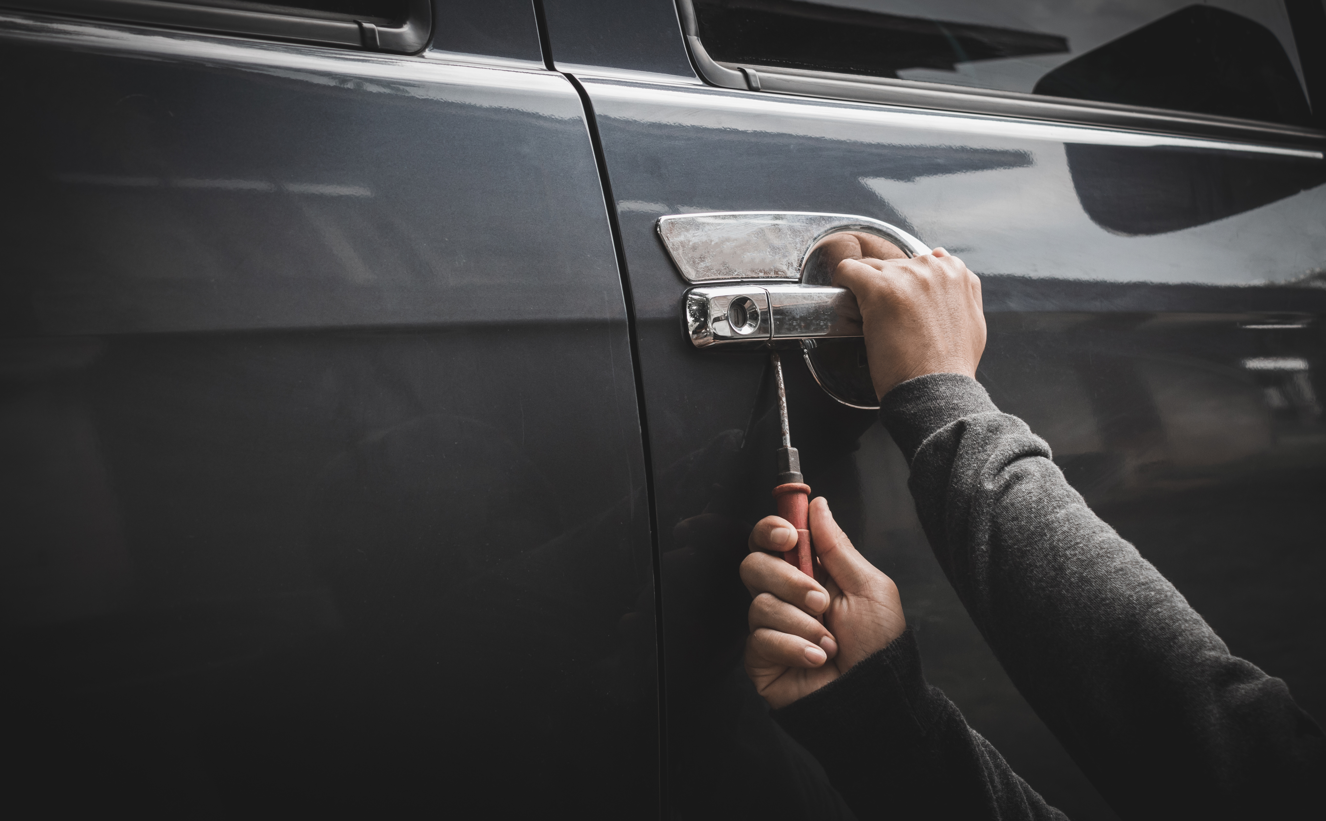 Thief using screwdriver to open car door